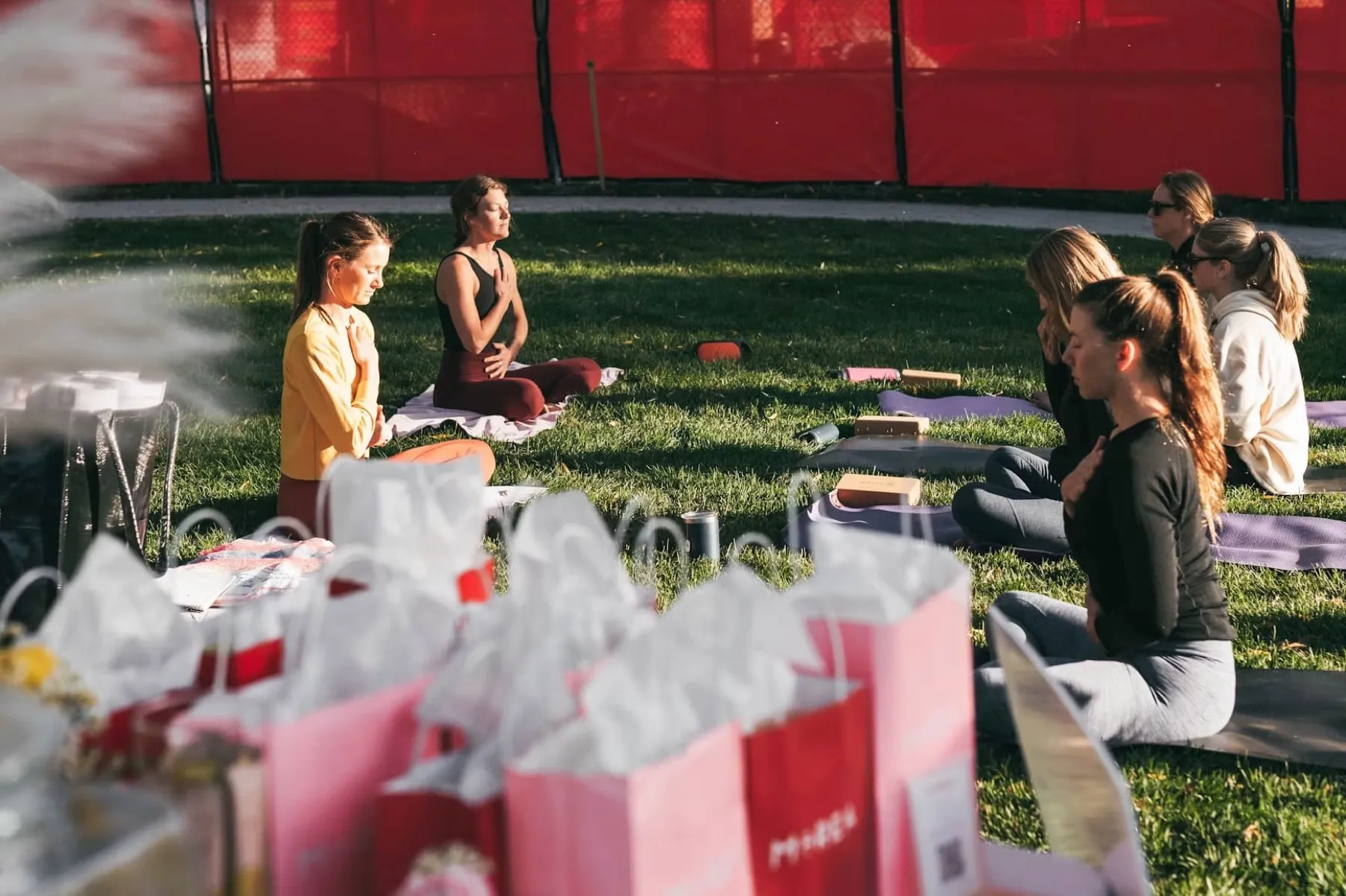 An outdoor wellness session on a lawn with event gift bags in the foreground